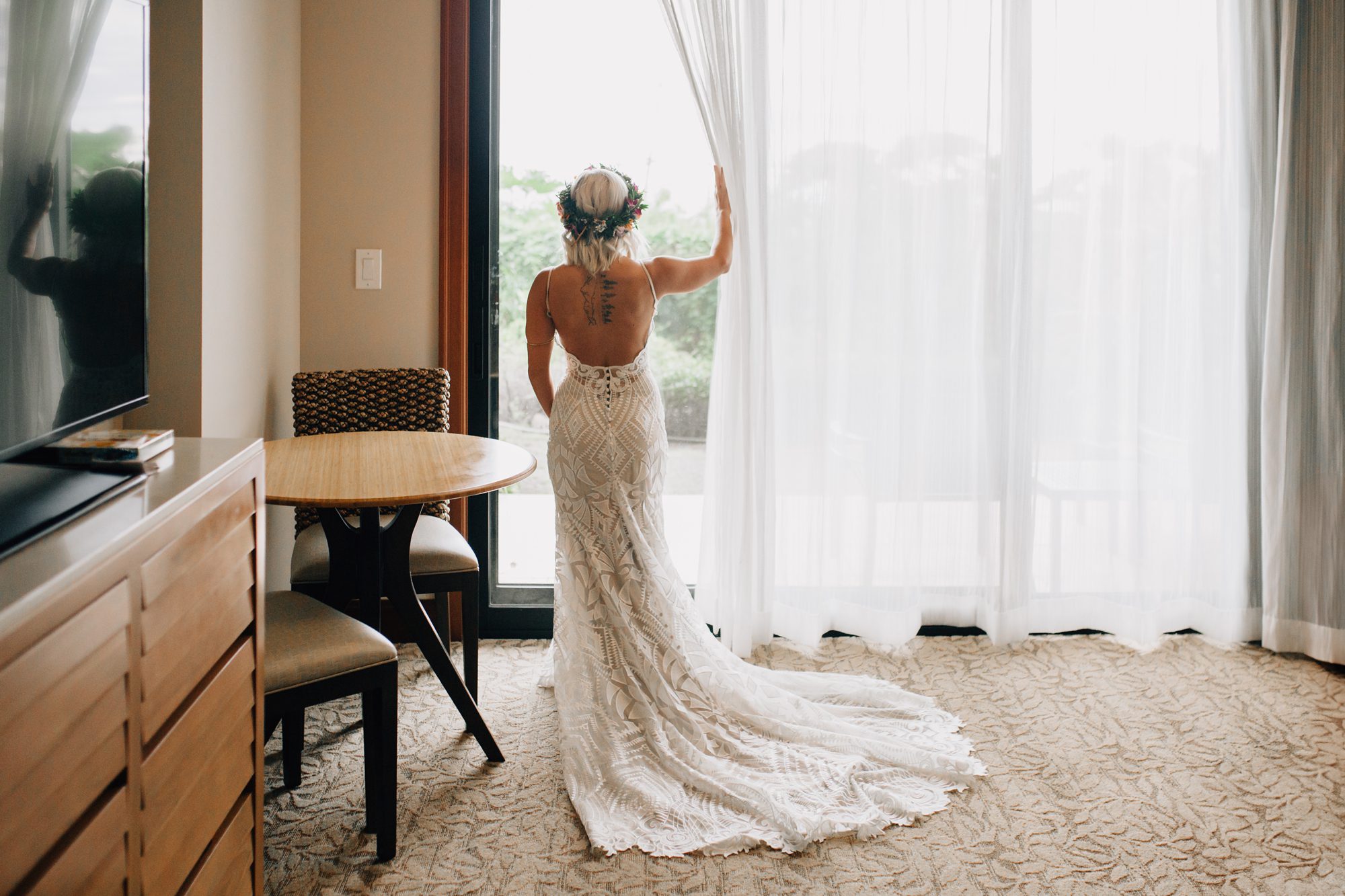 Bride looks out the window of her hotel room moments before her first look at Koloa Landing Resort.