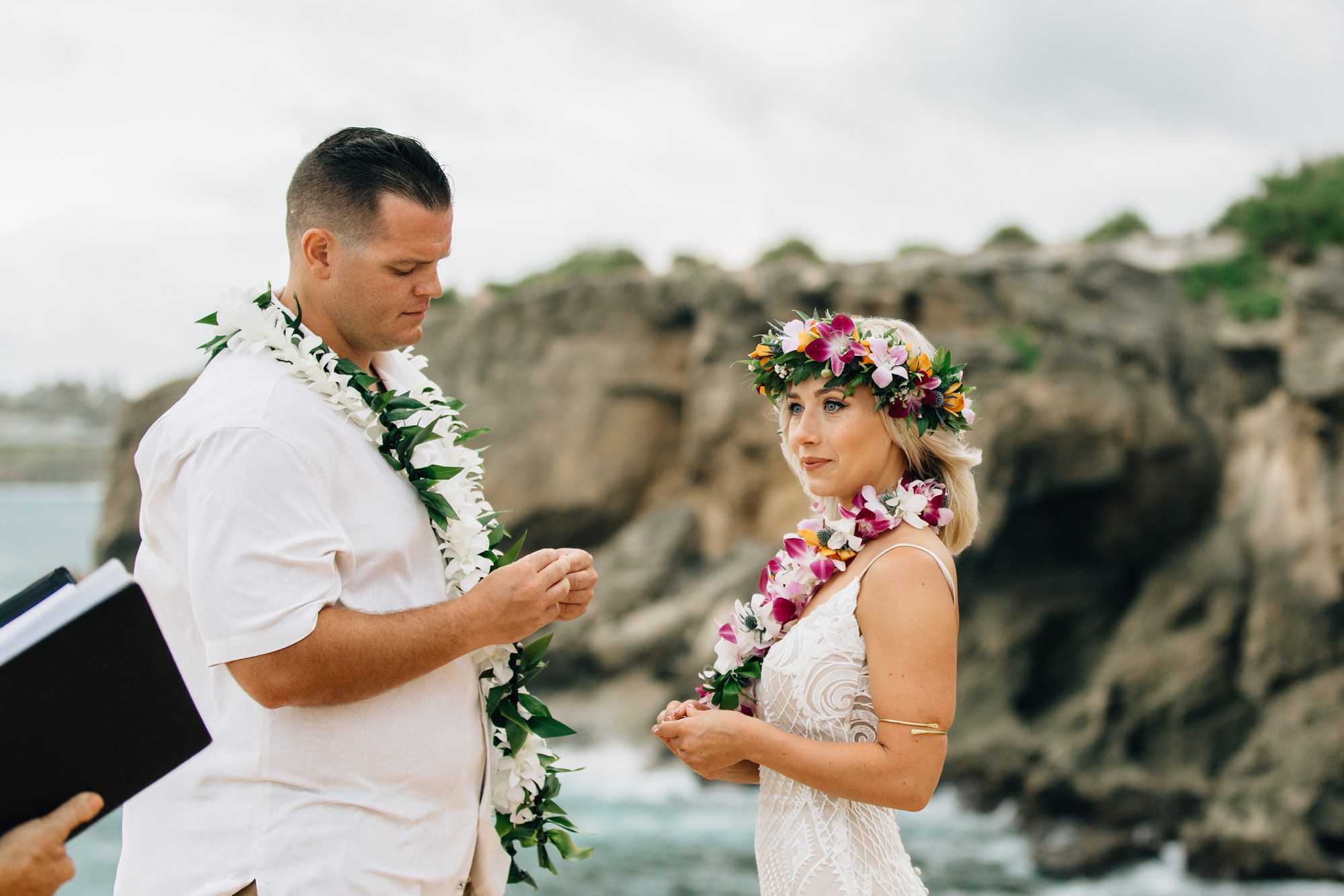 Groom shows emotion as he gazes at the bride's wedding ring that he is holding in his hand.