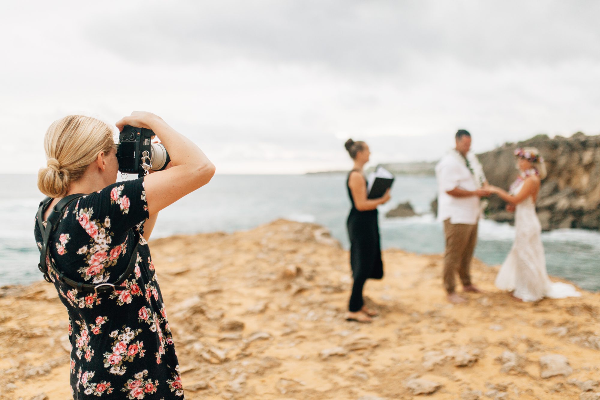 Photographer Lyndsey Kaye takes photos of a Kauai elopement on a cliff at Shipwreck Beach.