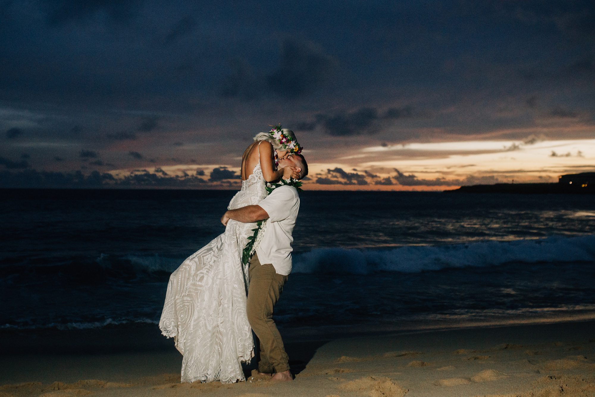 Bride and groom on Shipwreck Beach at dusk.
